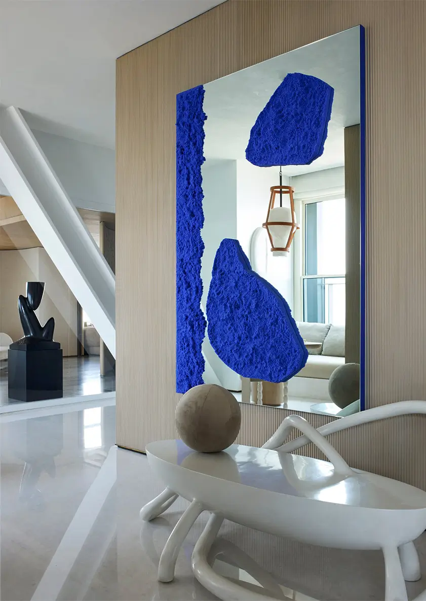 Curating complimenting delicate wall hung mirror artwork with contrasting blue details that compliments contemporary wall paneling to home entrance hallway